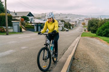 Fototapeta premium 18/04/2020 Asian woman making uphill with mountain bike. A woman very tired and stop on street At Oamaru, New Zealand.