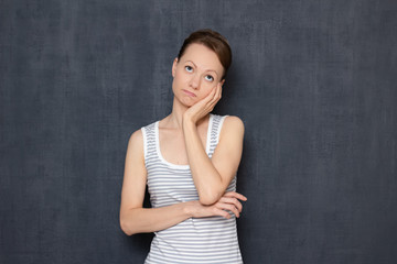 Portrait of thoughtful tired young woman propping up head with hand