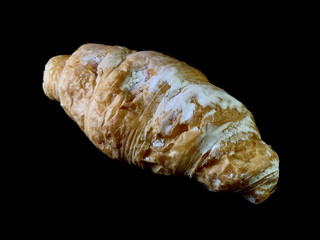 Tasty french croissant, on black background. Air pastries with cream filling inside. Bun for dessert with icing sugar.