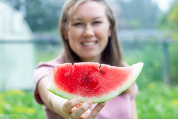 Joyful woman holds a slice of watermelon in front of her. Summer holiday concept. Healthy eating....