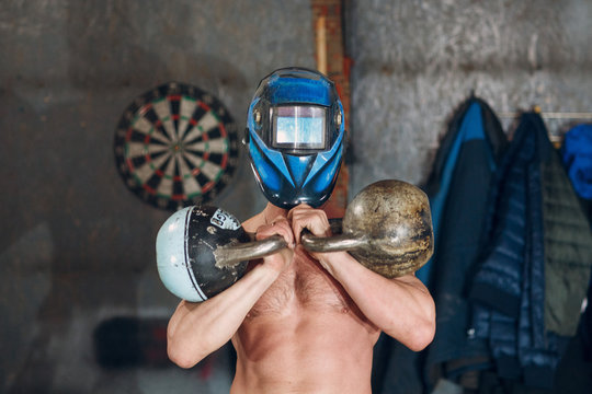 Man In Welding Mask Training With Kettlebells.