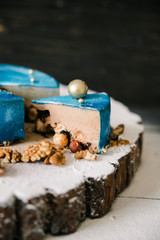 cut mousse chocolate cake with nuts space view on a wooden slice on a black wood background