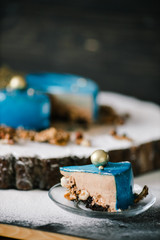 cut mousse chocolate cake with nuts space view with sparklers on a wooden slice on a black wood background