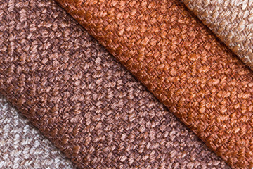 A set of colored samples of upholstery fabric for furniture in stock. Background from rolls of multi-colored fabric, empty template. Fabric Gun for furniture upholstery, orange, beige, brown.