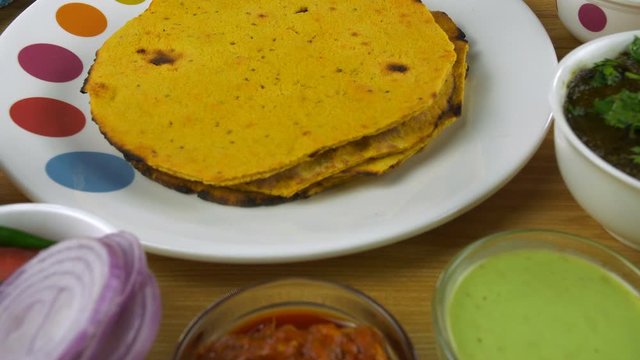 Makki ki Roti and saag - Punjabi cuisine consumed during the winter season in India. Tilt shot of freshly made Makki ki Roti and Sarson ka saag served with salad  pickle  and green chutney - food c...