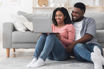Obraz premium Millennial Black Couple Relaxing With Laptop At Home, Watching Movies Together