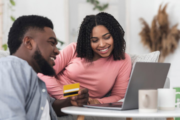 Happy black couple using laptop and credit card for online shopping