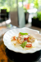 Scallop with tomatoes and sauce and basil