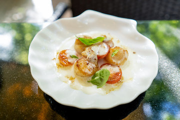 Scallop with tomatoes and sauce and basil