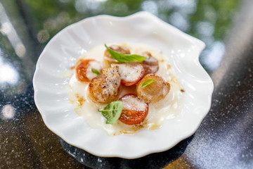 Scallop with tomatoes and sauce and basil