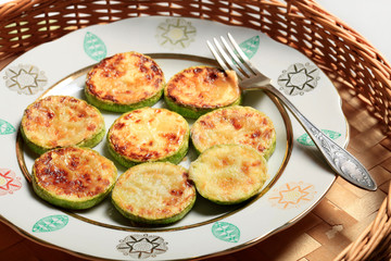 Homemade Fried sliced courgette. Zucchini cut into pieces served on plate or bowl on wicker wooden table. Vegetable vegetarian food dish