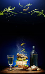 A sandwich in Ukrainian style with slice of bacon on blue background with flying ingredients...