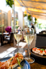 Two glasses of white wine with bruschetts on summer terrace bokeh sunlight leaf cafe