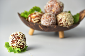 Middle Eastern, ball-shaped dessert made of dried apricots with various coatings. Energy balls. Coconut shell plate, salad leaves.