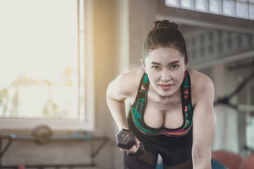 Asian beautiful woman is lifting double in the gym, She smile happily in exercise because it makes her shapely, the concept of exercise, lose weight, strengthen muscles.