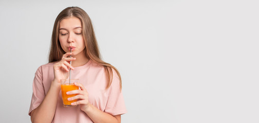 Fototapeta premium Happy young girl drinking orange infused water on white
