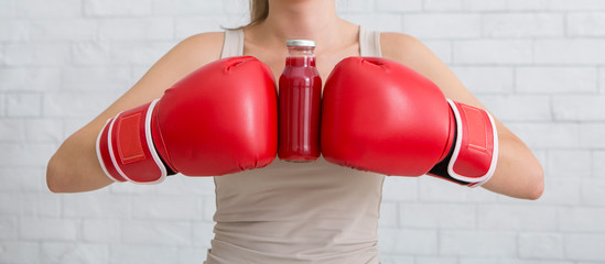 Woman in boxing gloves holding red detox smoothie