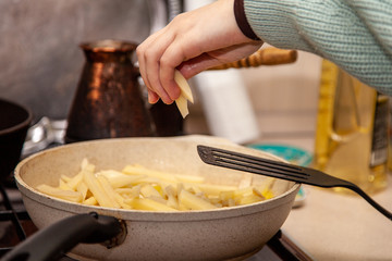 cooking fried potatoes in a pan on a stove