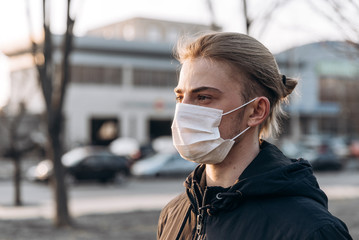 A young man wearing a medical mask in the street during covid-19 pandemic
