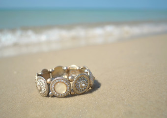 a golden diamante bracelet lying on the sea beach