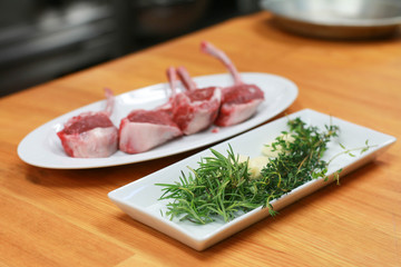 Raw beef bone rib-eye steak on a plate with onion, garlic and garnish ready to cook.