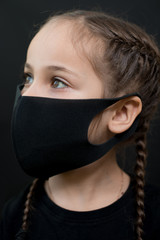 Girl with red eyes and black a medical mask on a black background, copy space. Concept of people who are isolated in a coronavirus quarantine.
