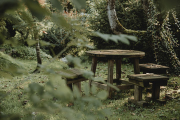 Naklejka premium Old wooden garden furniture in the green tranquil garden with the zen atmosphere during the summer morning