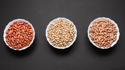 Assortment beans in round bowls on black background