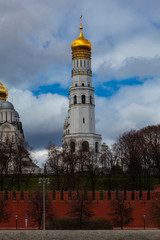 Fototapeta na wymiar The bell tower of Ivan the Great on the territory of the Moscow Kremlin. In the foreground is a fortress wall