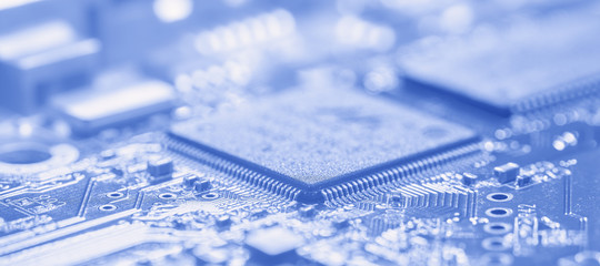 Microchip and printed circuit board in soft focus. The photo toned blue.