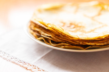 pancakes on a white tablecloth and plate a sunny day with sun glare