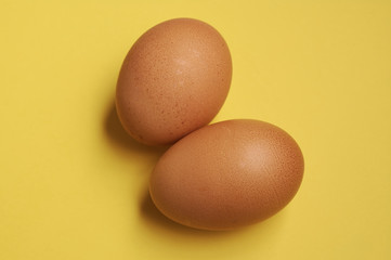 two home-grown organic chicken eggs on a yellow background