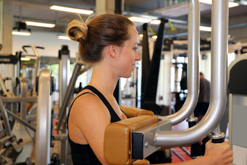 Junge Frau beim Gerätetraining im Fitnessstudio