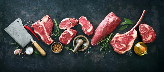 Foto op Plexiglas Verscheidenheid aan rauwe biefstukken om te grillen met kruiden en keukengerei © Alexander Raths