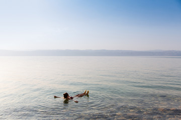 Girl is relaxing and swimming in the water of the Dead Sea in Jordan