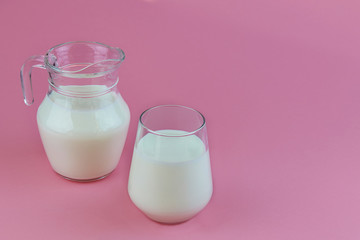Organic probiotic kefir or yogurt with probiotics in glass and jug on pink background. Homemade cold fermented dairy drink. 