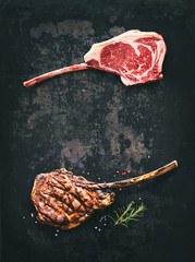 Black angus Tomahawk beef steaks raw and grilled on dark rustic background