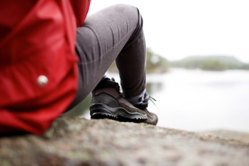 person sitting with hiking shoes by water in rural area