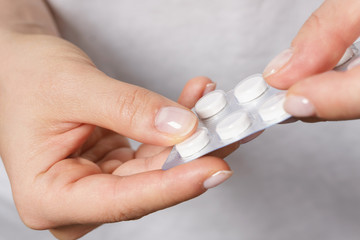 Female hand with a pill in foil packaging