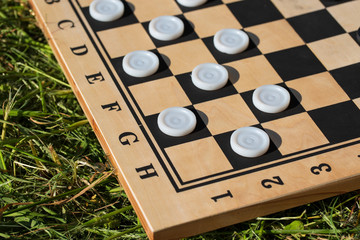 wooden checkerboard with checkers on the grass