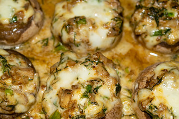 Mushrooms baked in the oven with cheese, green onions and dill. Close up.