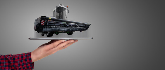 Farmer holding a tablet with a combine harvester. Augmented reality and digital transformation in agriculture. Smart farming concept