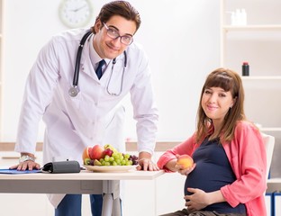 Obraz na płótnie Canvas Pregnant woman visiting doctor discussing healthy diet