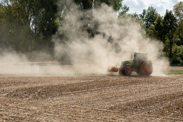 Fototapeta premium Symbolbild für Dürre und Wassermangel, Landwirt wirbelt mit Traktor Staub auf