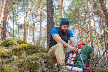 A man in the woods packs his things in a backpack. Halt in the forest.