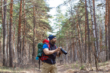 Fototapeta premium Bird watcher walks through the woods with a camera.