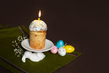 Easter cake with burning candles with colored eggs on a stand in the form of a hare. Easter decor.