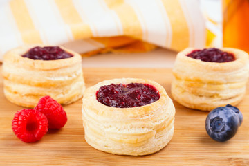 Danish pastry cake with cranberry jam and fresh blueberry and raspberry on the table. Sunny breakfast.