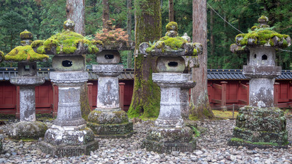 Fototapeta na wymiar Stone lanterns with refreshing green moss on gravel yard in japanese temple garden for background, copy space
