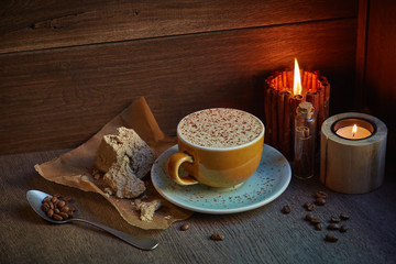 hot coffee drink with halva and spices on the wooden table next to the candles, homemade recipe, vintage concept 